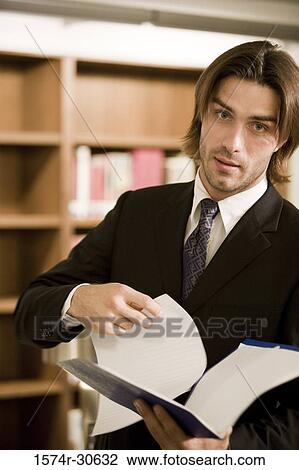 Stock Image - Portrait of a businessman holding a file in an office. Fotosearch