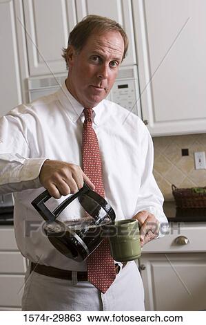 Stock Image - Portrait of a businessman pouring coffee into a coffee mug. Fotosearch