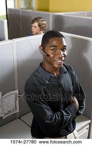 Portrait of a businessman using headset in an office with colleague in the background View Large Photo Image Stock Image - Portrait of a businessman using headset in an office with colleague in the background. Fotosearch