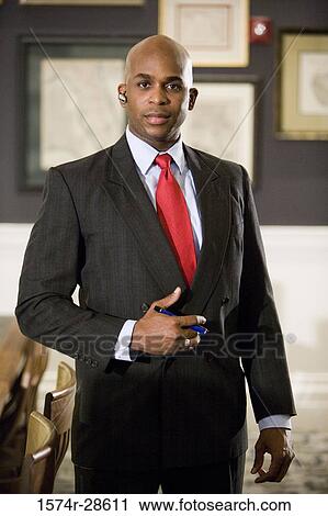Stock Image - Portrait of a businessman with handsfree device standing in an office. Fotosearch