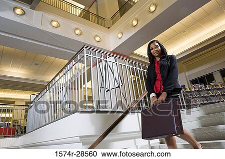 Stock Image - Portrait of a businesswoman descending on staircase in an office. Fotosearch
