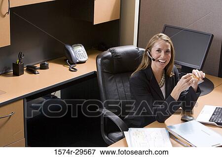 Portrait of a businesswoman sitting by a computer in an office View Large Photo Image Stock Photo - Portrait of a businesswoman sitting by a computer in an office. Fotosearch