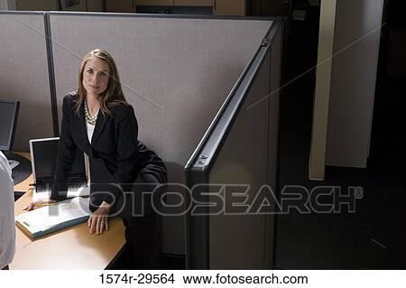 Picture - Portrait of a businesswoman sitting on table in an office. Fotosearch