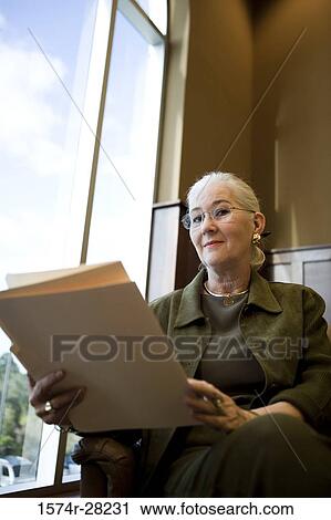 Portrait of a businesswoman sitting on armchair and holding file in an office View Large Photo Image Stock Image - Portrait of a businesswoman sitting on armchair and holding file in an office. Fotosearch