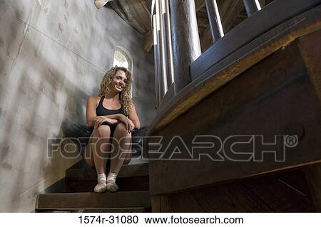 Stock Image - Portrait of a cheerful ballet dancer sitting on wooden staircase. Fotosearch