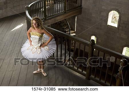 Stock Photography - Portrait of a cheerful ballet dancer standing on hardwood floor with hands on hip. Fotosearch
