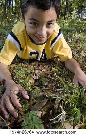 Portrait of a cheerful boy lying on grass by a frog View Large Photo Image Picture - Portrait of a cheerful boy lying on grass by a frog. Fotosearch
