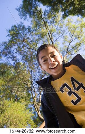 Portrait of a cheerful boy smiling against a tree View Large Photo Image Stock Image - Portrait of a cheerful boy smiling against a tree. Fotosearch