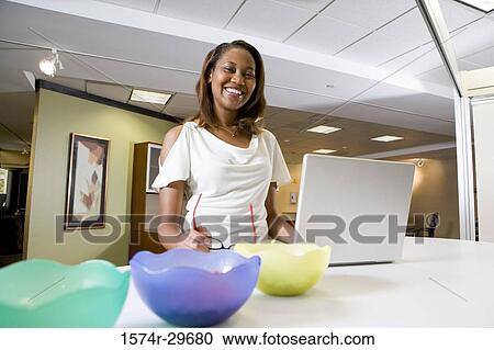 Portrait of a cheerful businesswoman standing in front of a laptop View Large Photo Image Stock Image - Portrait of a cheerful businesswoman standing in front of a laptop. Fotosearch