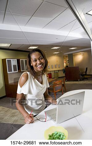Portrait of a cheerful businesswoman standing in front of a laptop View Large Photo Image Stock Image - Portrait of a cheerful businesswoman standing in front of a laptop. Fotosearch