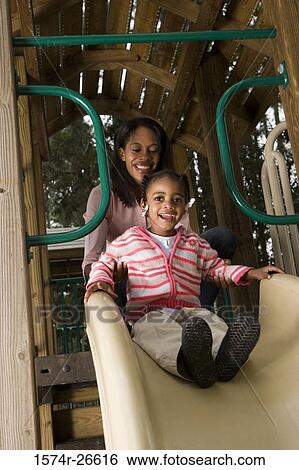 Portrait of a cheerful daughter playing with her mother on slide at park View Large Photo Image Stock Photograph - Portrait of a cheerful daughter playing with her mother on slide at park. Fotosearch