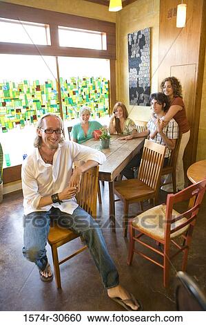Stock Image - Portrait of a cheerful family sitting together by table. Fotosearch