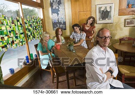 Stock Image - Portrait of a cheerful family sitting together by table. Fotosearch