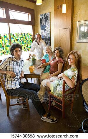 Portrait of a cheerful family sitting together by table View Large Photo Image Stock Photo - Portrait of a cheerful family sitting together by table. Fotosearch