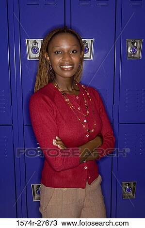 Portrait of a cheerful female teacher standing by locker in corridor View Large Photo Image Stock Image - Portrait of a cheerful female teacher standing by locker in corridor. Fotosearch