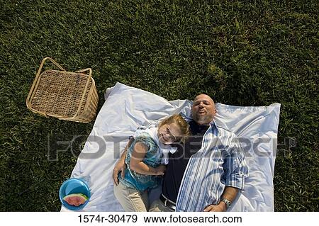 Portrait of a cheerful girl lying on blanket by her father View Large Photo Image Stock Photo - Portrait of a cheerful girl lying on blanket by her father. Fotosearch