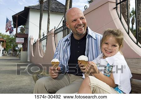 Portrait of a cheerful girl sitting by her father and holding an ice cream cone View Large Photo Image Stock Image - Portrait of a cheerful girl sitting by her father and holding an ice cream cone. Fotosearch