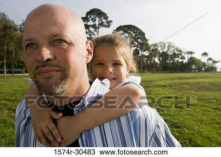 Stock Image - Portrait of a cheerful girl piggybacking on father. Fotosearch