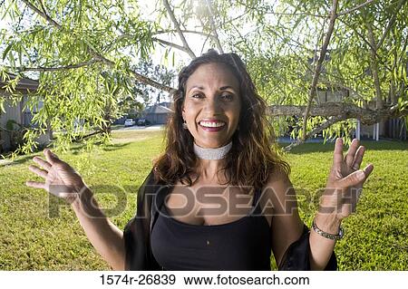 Stock Photo - Portrait of a cheerful mature woman standing in the lawn. Fotosearch