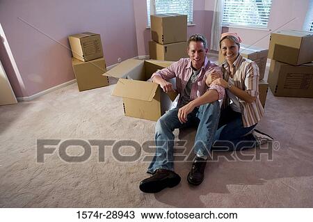 Portrait of a cheerful mid adult couple sitting by cardboard boxes in a house View Large Photo Image Stock Image - Portrait of a cheerful mid adult couple sitting by cardboard boxes in a house. Fotosearch