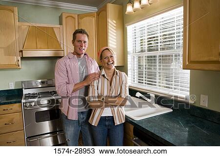 Portrait of a cheerful mid adult couple standing by kitchen counter in the kitchen View Large Photo Image Stock Image - Portrait of a cheerful mid adult couple standing by kitchen counter in the kitchen. Fotosearch