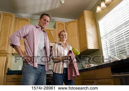 Portrait of a cheerful mid adult couple standing by kitchen counter in the kitchen View Large Photo Image Stock Image - Portrait of a cheerful mid adult couple standing by kitchen counter in the kitchen. Fotosearch