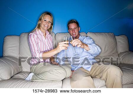 Portrait of a cheerful mid adult couple toasting wineglasses on sofa View Large Photo Image Stock Image - Portrait of a cheerful mid adult couple toasting wineglasses on sofa. Fotosearch