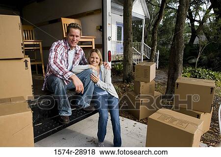 Stock Photo - Portrait of a cheerful mid adult couple sitting in moving van. Fotosearch