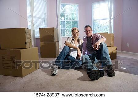 Portrait of a cheerful mid adult couple sitting by cardboard boxes in a house View Large Photo Image Stock Photo - Portrait of a cheerful mid adult couple sitting by cardboard boxes in a house. Fotosearch