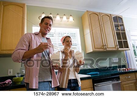 Portrait of a cheerful mid adult couple eating fast food in the kitchen View Large Photo Image Stock Photo - Portrait of a cheerful mid adult couple eating fast food in the kitchen. Fotosearch