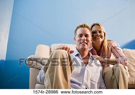 Portrait of a cheerful mid adult couple sitting on a sofa View Large Photo Image Stock Photograph - Portrait of a cheerful mid adult couple sitting on a sofa. Fotosearch