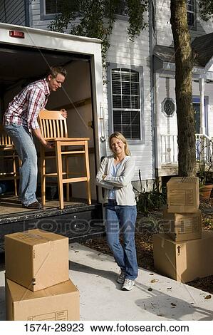 Portrait of a cheerful mid adult woman standing while mid adult man unloading chairs from the moving van View Large Photo Image Stock Image - Portrait of a cheerful mid adult woman standing while mid adult man unloading chairs from the moving van. Fotosearch