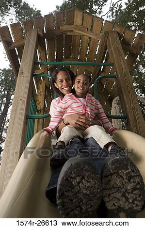 Portrait of a cheerful mother playing with her daughter on slide at park View Large Photo Image Stock Image - Portrait of a cheerful mother playing with her daughter on slide at park. Fotosearch