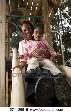 Portrait of a cheerful mother playing with her daughter on slide at park View Large Photo Image Stock Photography - Portrait of a cheerful mother playing with her daughter on slide at park. Fotosearch