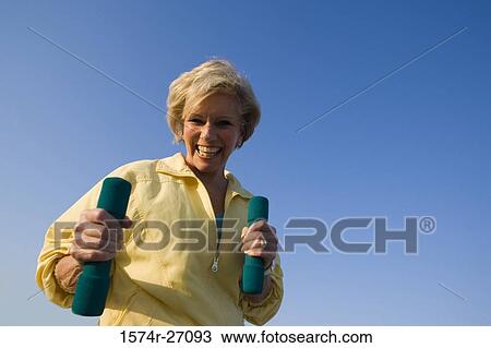 Portrait of a cheerful senior woman holding dumbbells View Large Photo Image Stock Image - Portrait of a cheerful senior woman holding dumbbells. Fotosearch