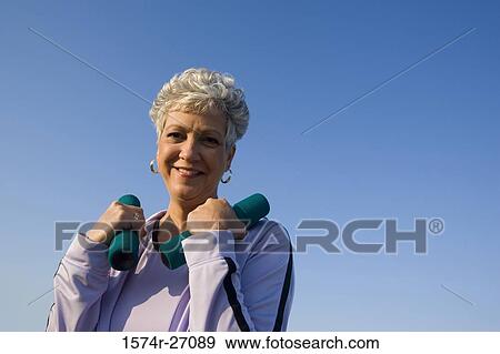 Portrait of a cheerful senior woman holding dumbbells View Large Photo Image Stock Photo - Portrait of a cheerful senior woman holding dumbbells. Fotosearch