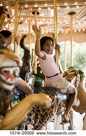 Portrait of a cheerful teenage girls sitting on a carousel and waving hands View Large Photo Image Stock Photo - Portrait of a cheerful teenage girls sitting on a carousel and waving hands. Fotosearch
