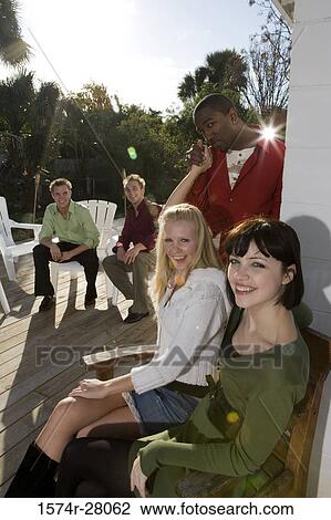 Portrait of a cheerful women sitting on armchairs while men smiling in background View Large Photo Image Stock Image - Portrait of a cheerful women sitting on armchairs while men smiling in background. Fotosearch