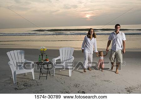 Portrait of a cheerful young couple walking on the beach with their daughter View Large Photo Image Stock Photo - Portrait of a cheerful young couple walking on the beach with their daughter. Fotosearch
