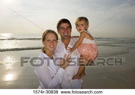 Portrait of a cheerful young couple with their daughter on the beach View Large Photo Image Stock Photo - Portrait of a cheerful young couple with their daughter on the beach. Fotosearch