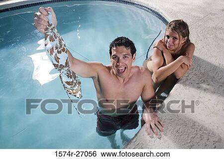 Portrait of a cheerful young man holding bikini top of young woman in swimming pool View Large Photo Image Stock Photograph - Portrait of a cheerful young man holding bikini top of young woman in swimming pool. Fotosearch