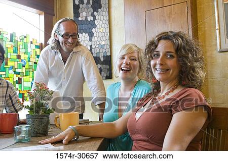 Stock Photo - Portrait of a cheerful young woman sitting with parents by table. Fotosearch