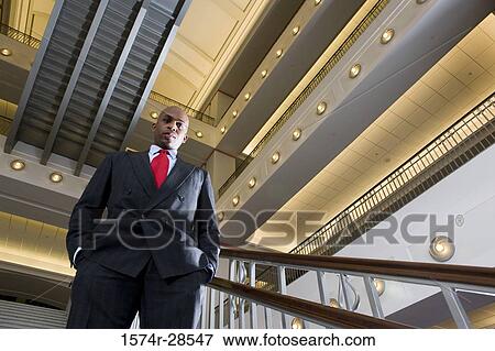 Stock Photo - Portrait of a contemplative businessman standing on staircase in an office. Fotosearch