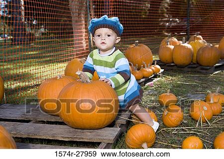 Portrait of a cute boy in warm clothing leaning on pumpkin View Large Photo Image Stock Photo - Portrait of a cute boy in warm clothing leaning on pumpkin. Fotosearch