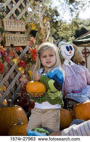 Portrait of a cute girl in warm clothing holding a pumpkin View Large Photo Image Stock Image - Portrait of a cute girl in warm clothing holding a pumpkin. Fotosearch