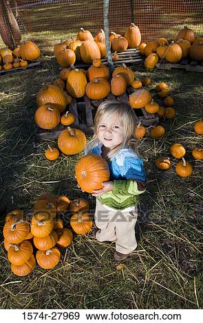 Stock Photo - Portrait of a cute girl in warm clothing holding a pumpkin. Fotosearch