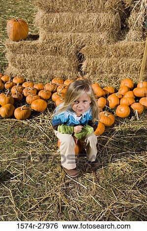Portrait of a cute girl in warm clothing sitting on a pumpkin View Large Photo Image Stock Photograph - Portrait of a cute girl in warm clothing sitting on a pumpkin. Fotosearch