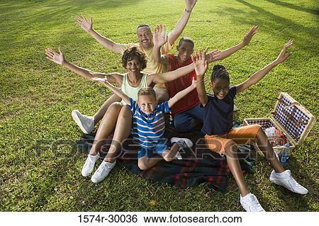 Portrait of a family sitting with arms raised on blanket at park View Large Photo Image Stock Photograph - Portrait of a family sitting with arms raised on blanket at park. Fotosearch