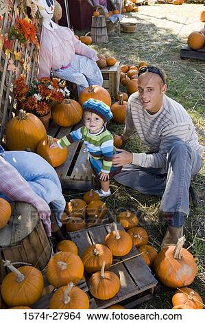 Portrait of a father holding his son amid pumpkin View Large Photo Image Picture - Portrait of a father holding his son amid pumpkin. Fotosearch
