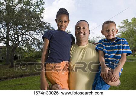 Portrait of a father holding their children at park View Large Photo Image Stock Photograph - Portrait of a father holding their children at park. Fotosearch